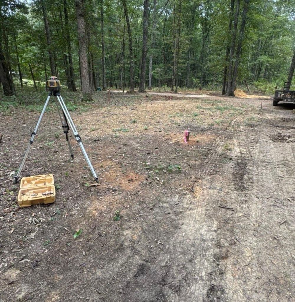 Surveying equipment set up in a wooded area for land measurement and analysis.