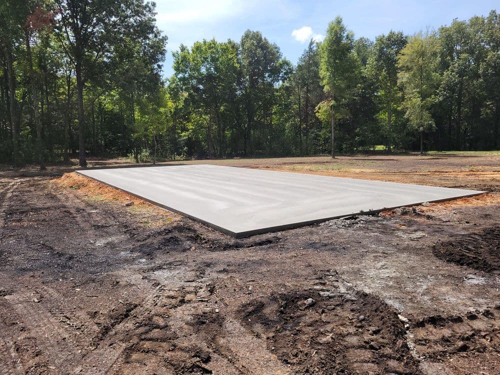 Concrete foundation slab in a wooded area ready for construction.