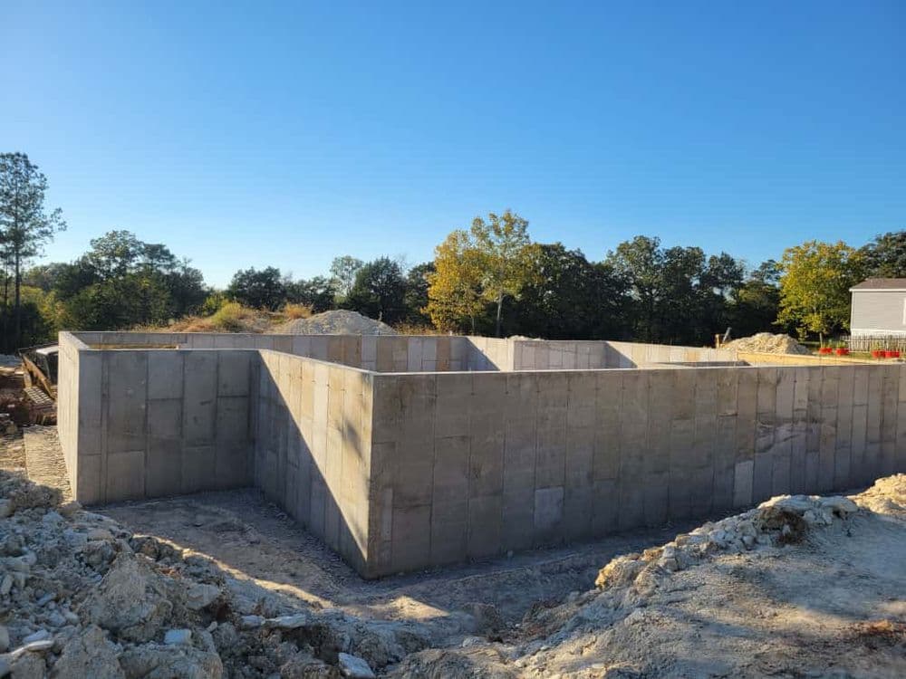 Concrete foundation construction in a rural setting under clear blue skies.